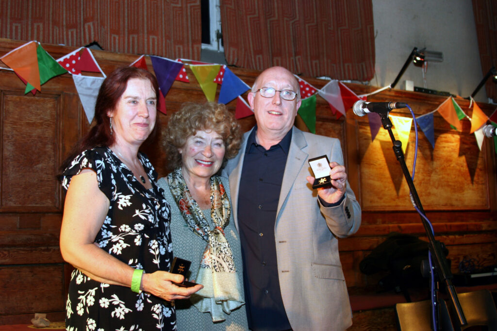 Katie and John Howson receiving their Gold Badge Awards from EFDSS President Shirley Collins. Photo by J Halliday. From the EATMT website.